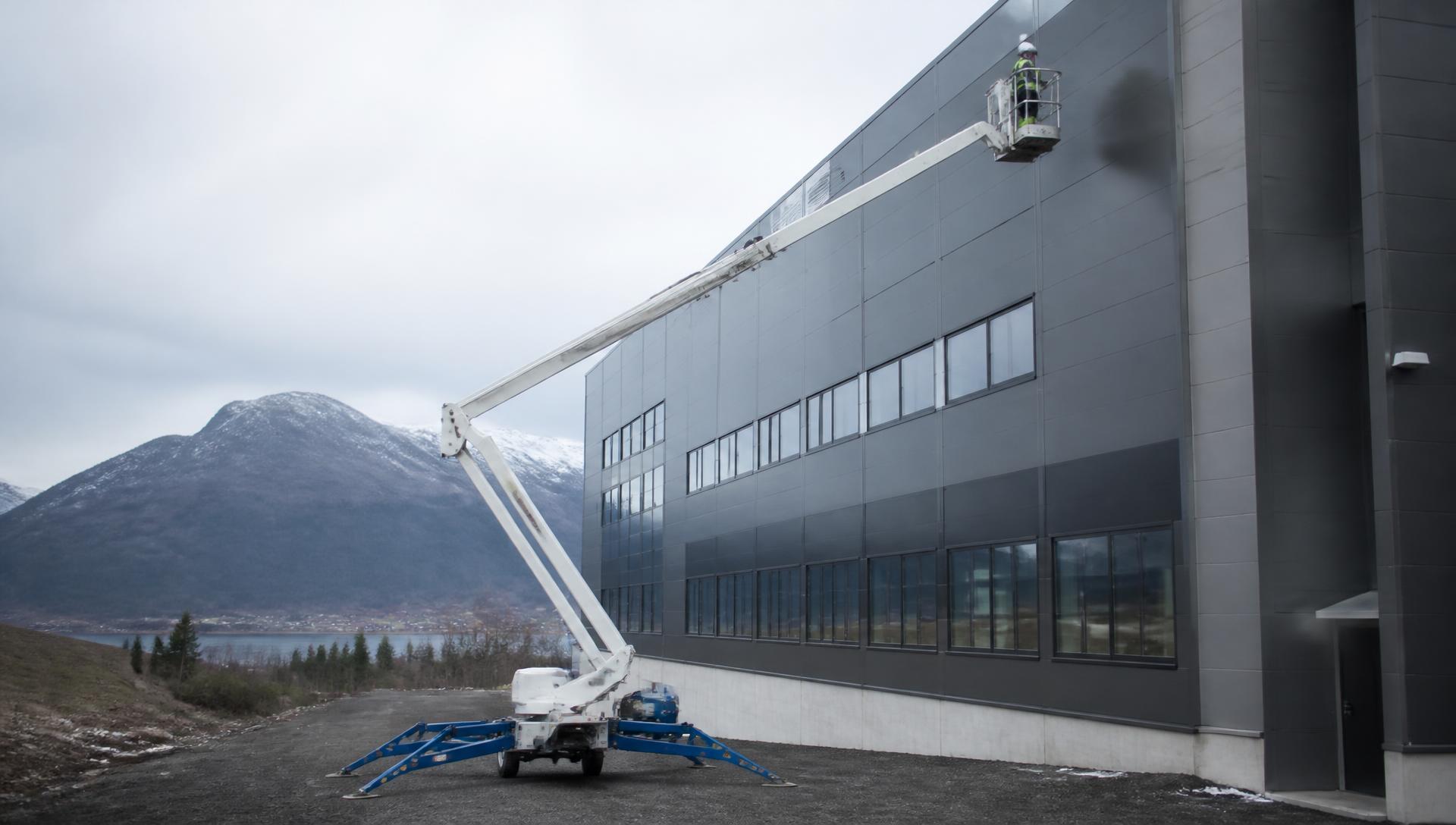 Lift i arbeid mot fasaden på et industribygg